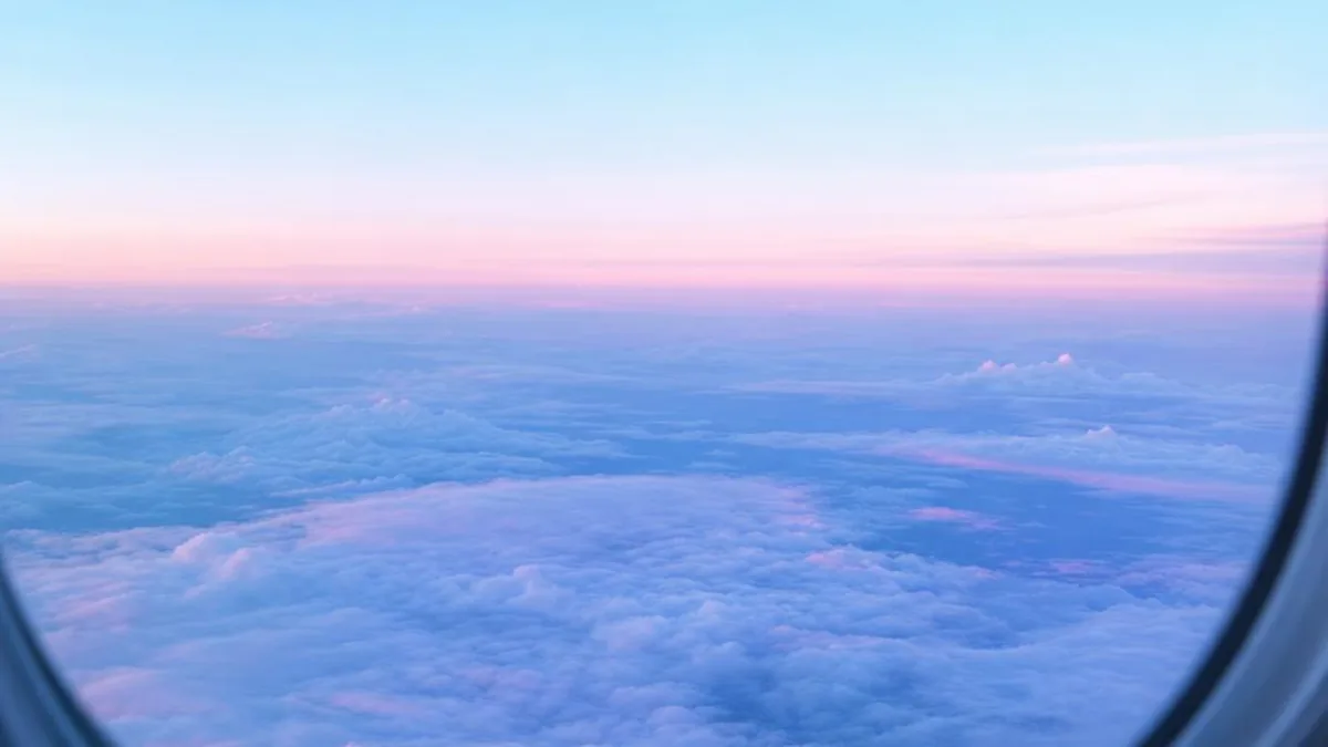 Pale blue and pink clouds seen through an aircraft window