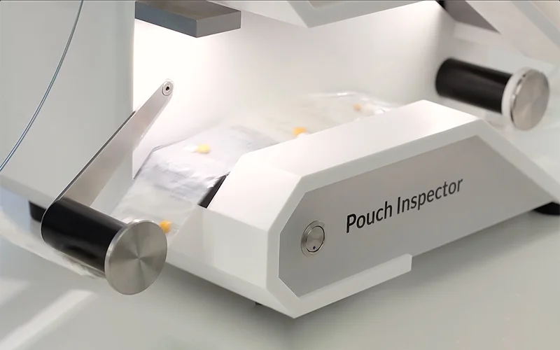 Pouch inspection machine scanning a strip of sealed medication pouches